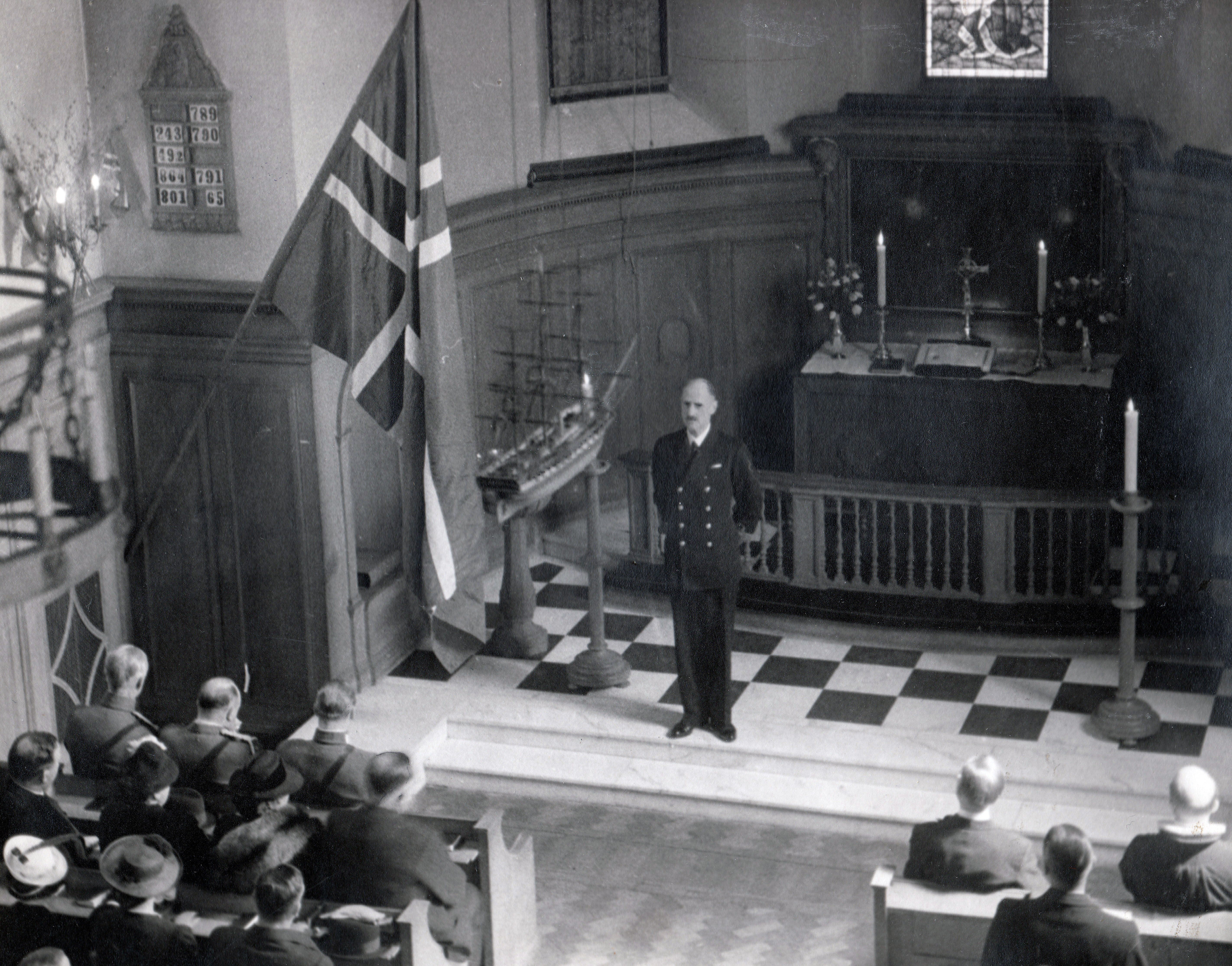 Kong Haakon taler i Sjømannskirken ved gudstjenesten i London 17. mai 1941. På første rad: kronprins Olav og adjunktene. Bak: statsminister Johan Nygaardsvold.