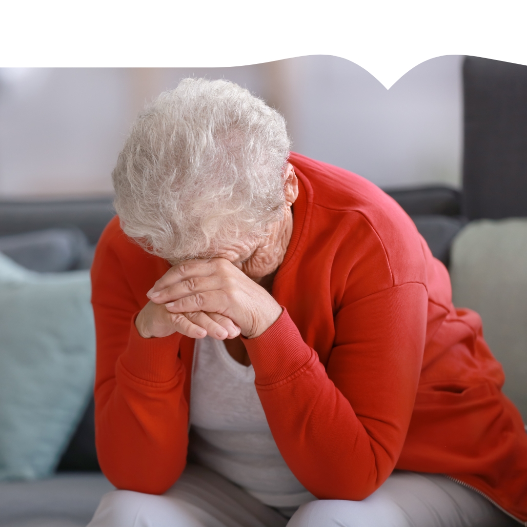 Illustrasjonsfoto av en eldre dame som sitter bøyd med hodet i hendene