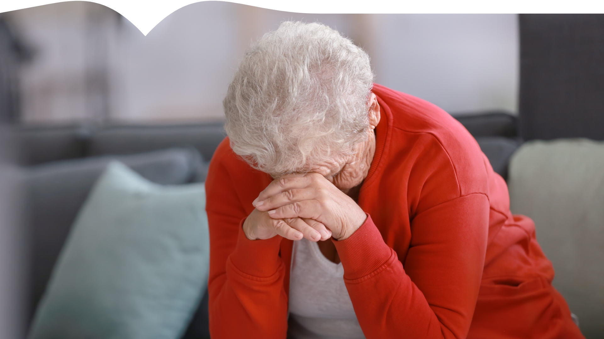Illustrasjonsfoto av en eldre dame som sitter bøyd med hodet i hendene